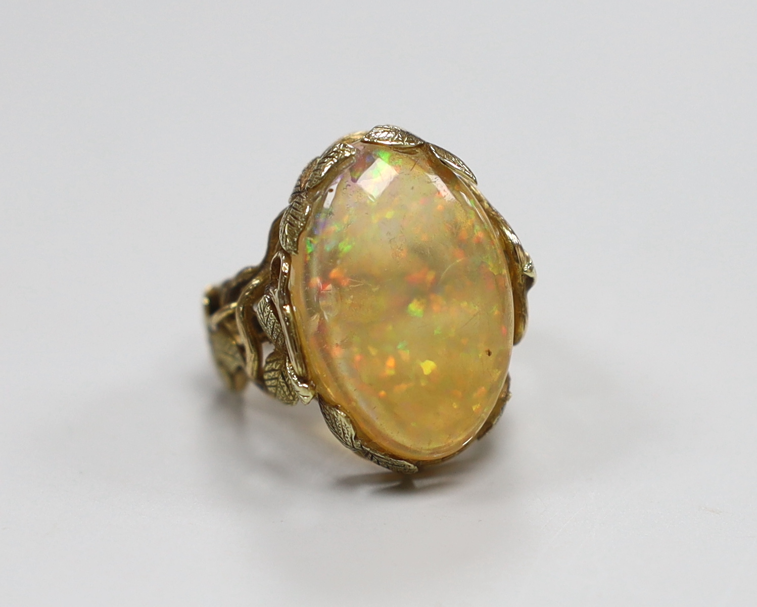 A yellow metal and oval jelly? opal set dress ring, with rustic foliate shank and setting, size L, gross weight 8.6 grams.